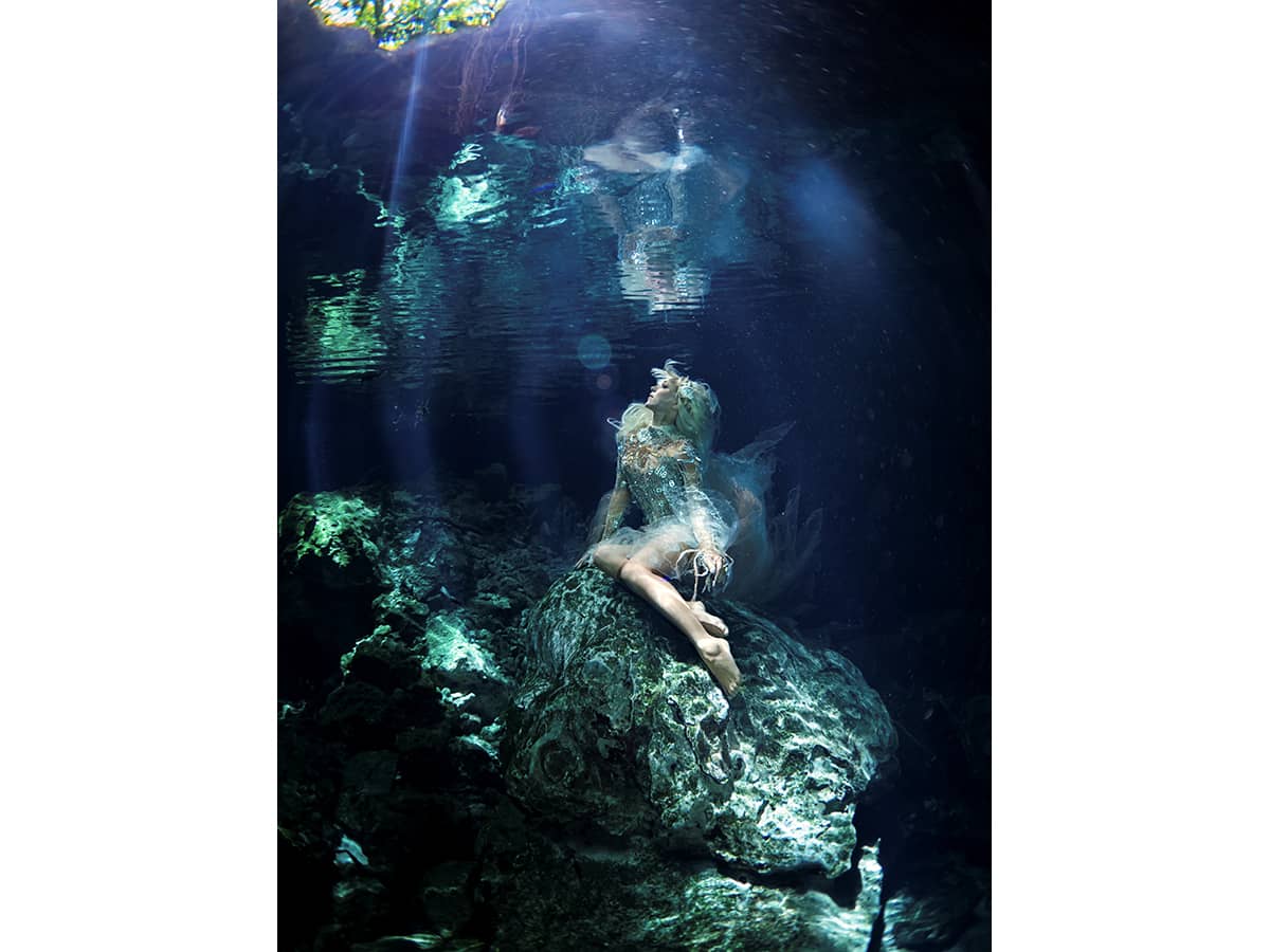 Underwatermodel sitting on a rock.